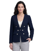 Woman wearing a navy blazer with silver buttons on a white background