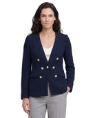 Woman wearing a navy blue blazer with silver buttons on a white background