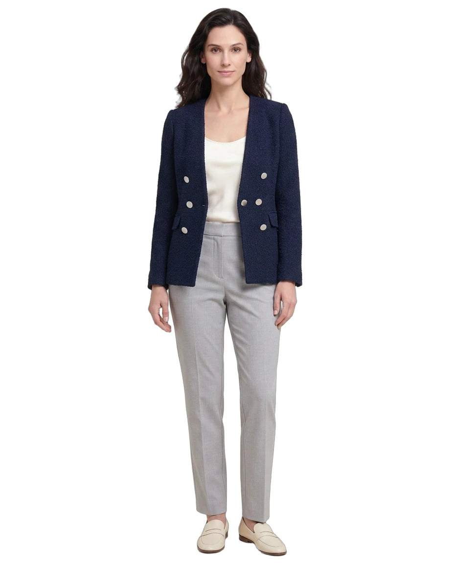 Woman wearing a navy blazer with white buttons, white top, and gray pants on a white background