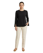 Woman wearing a black top with studded details and beige pants on a white background