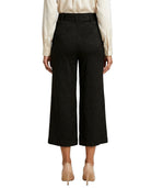 Person wearing black Calvin Klein wide-leg pants with a white shirt on a white background