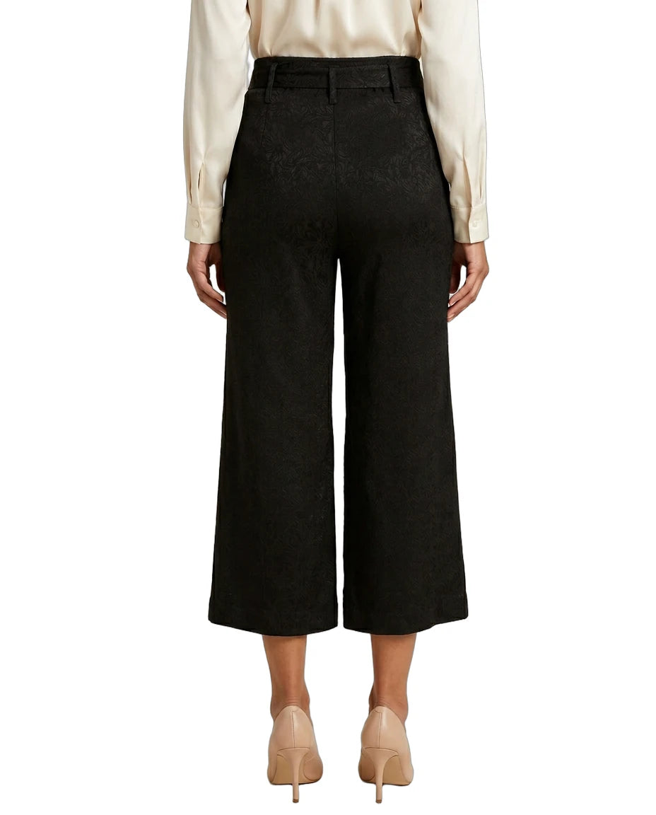 Person wearing black Calvin Klein wide-leg pants with a white shirt on a white background