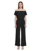 Woman wearing a Calvin Klien black off-shoulder jumpsuit on a white background