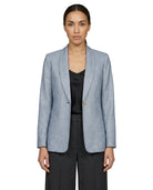 Woman wearing a light blue Calvin Klein  checkered blazer over a black top on a white background