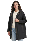 Woman wearing a black Calvin Klein coat with gold buttons on a white background