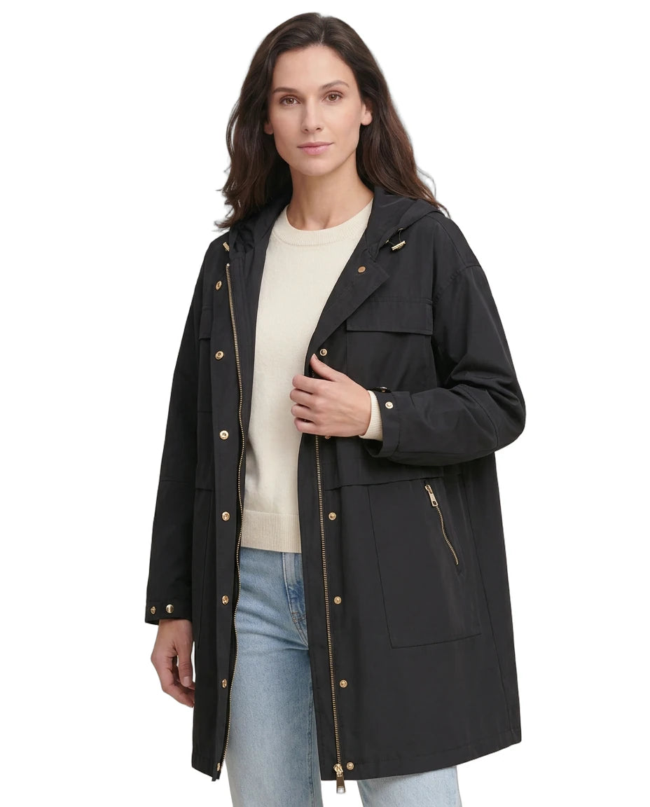 Woman wearing a black Calvin Klein coat with gold buttons on a white background