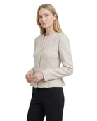 Woman wearing a Calvin Klein beige blazer and black pants on a white background