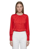 Person wearing a red blouse and white pants on a white background