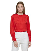 Woman wearing a red blouse with long sleeves and white pants on a white background