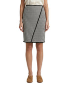 Person wearing a Calvin Klein black and white houndstooth patterned skirt with a plain background