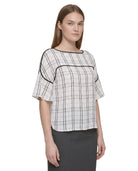 Woman wearing a Calvin Klein black and white checkered blouse with a plain background