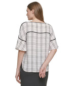 Woman wearing a Calvin Klein black and white checkered blouse with a plain background
