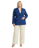 Woman wearing a Calvin Klein blue blazer and white pants on a white background
