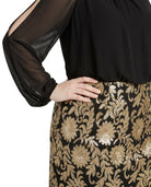 Woman wearing a Calvin Klein black and gold floral dress on a white background