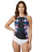 Woman wearing a floral Calvin Klein tankini top and white bottoms on a white background
