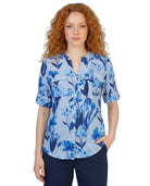 Woman wearing a blue floral patterned Calvin Klein blouse on a white background