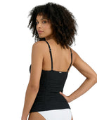 Woman wearing a black Calvin Klein tankini with thin straps on a white background