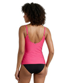 Woman wearing a pink Calvin Klein swimsuit with black bottoms on a white background
