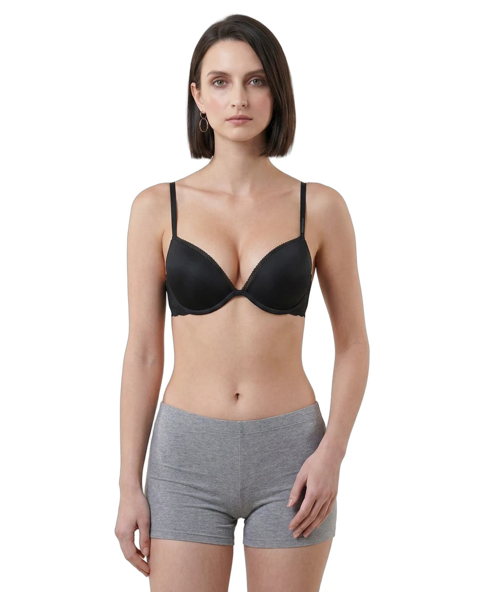 Woman wearing a black Calvin Klein bra and gray shorts on a white background