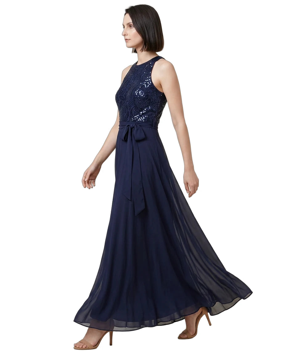 Woman wearing a navy blue Calvin Klein evening gown with sequin detailing on a white background