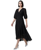 Woman wearing a black Calvin Klein dress with sheer sleeves on a white background
