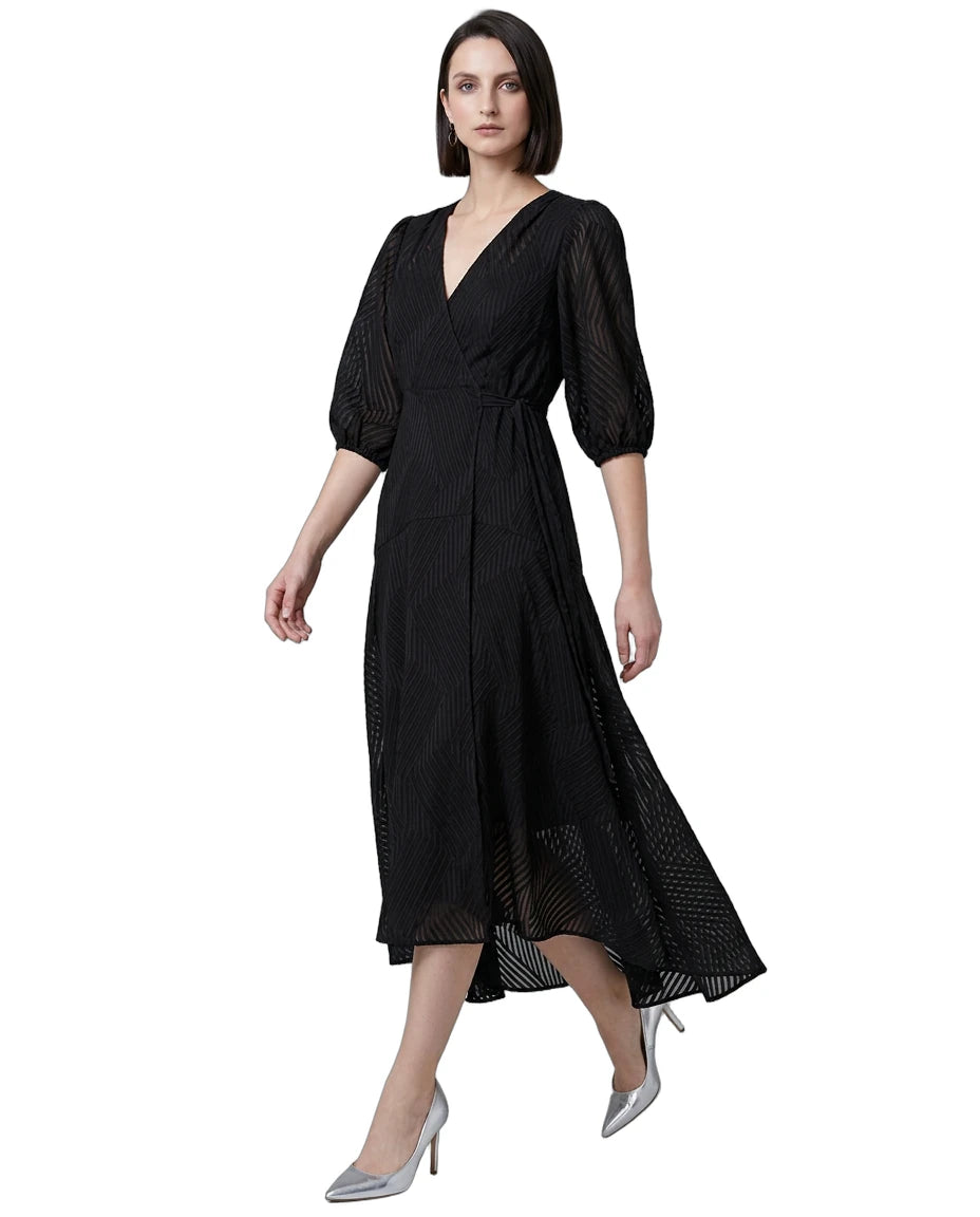 Woman wearing a black Calvin Klein dress with sheer sleeves on a white background