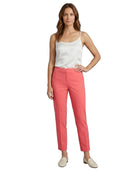 Woman wearing a white top and Calvin Klein coral pants on a white background