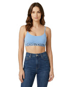 Woman wearing a Calvin Klein blue sports bra and jeans on a white background
