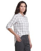 Woman wearing a white and black checkered Calvin Klein shirt with gray pants on a white background