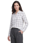 Woman wearing a white and gray checkered Calvin Klein shirt with gray pants on a white background
