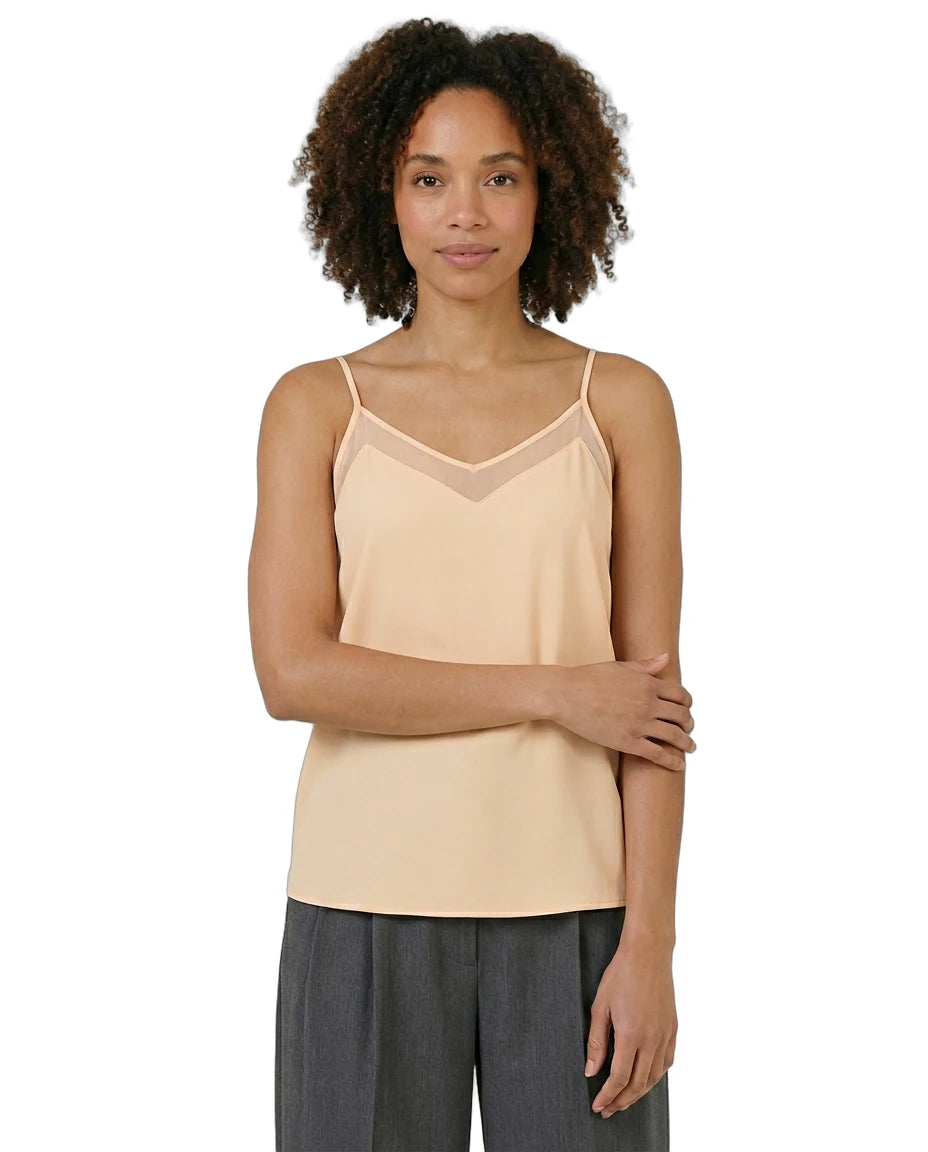 Woman wearing a beige camisole and gray pants on a white background