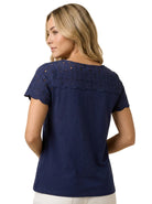 Back view of a blonde woman wearing the Charter Club petite navy blue cotton top showing the embroidered eyelet upper back and scalloped edges.