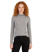 Woman wearing a gray turtleneck sweater and black pants on a white background