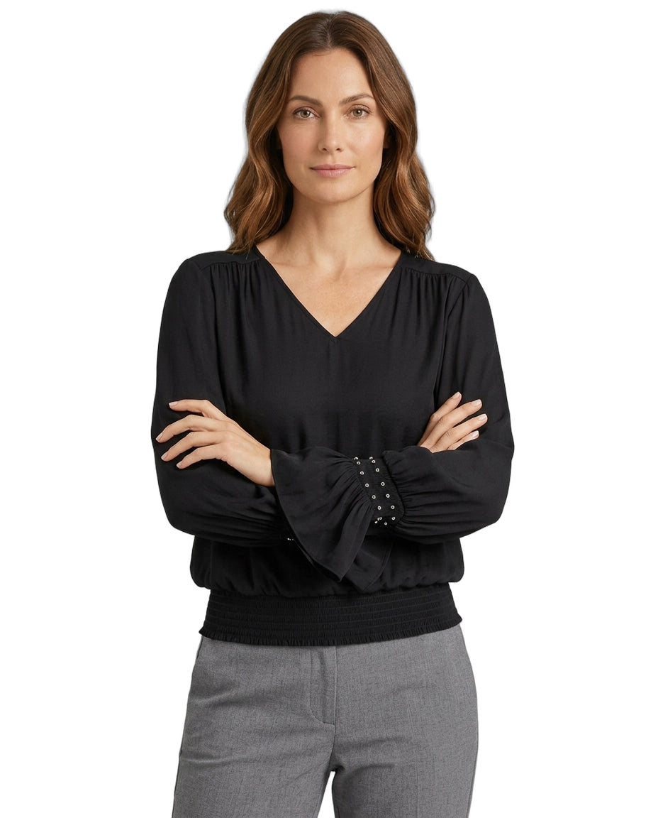 Woman wearing a black blouse with studded details on a white background