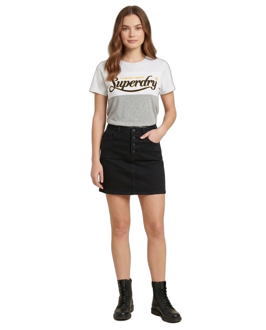 A woman modeling a light gray Superdry graphic t-shirt paired with a black denim mini skirt and black combat boots, set against a plain white background.
