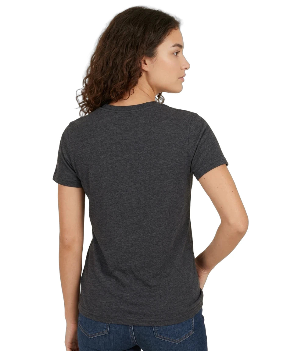 A woman with curly brown hair is shown from the back wearing a dark heather gray short-sleeve t-shirt and blue jeans against a plain white background.