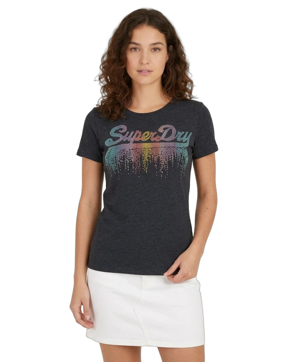 A woman modeling a dark charcoal heather t-shirt with a colorful 'SuperDry' graphic across the chest, paired with a white mini skirt, against a plain white background.
