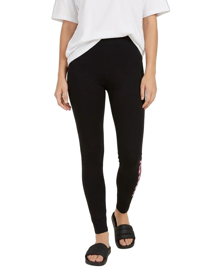 A model wearing black leggings with a pink and white graphic print on the side, styled with a white t-shirt and black slide sandals against a plain white background.