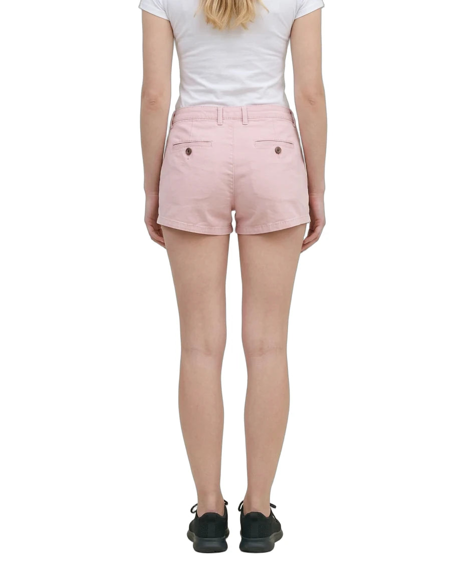 A model wearing light pink chino shorts, a white tank top, and black sneakers, shown from the waist down against a plain white background.
