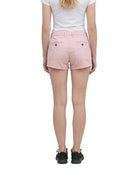 A model wearing light pink chino shorts, a white tank top, and black sneakers, shown from the waist down against a plain white background.