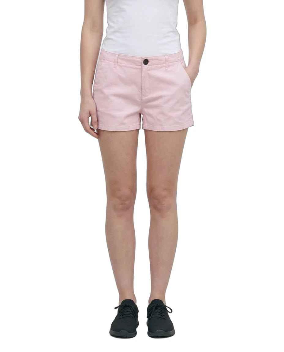 A model wearing light pink chino shorts, a white tank top, and black sneakers, shown from the waist down against a plain white background.